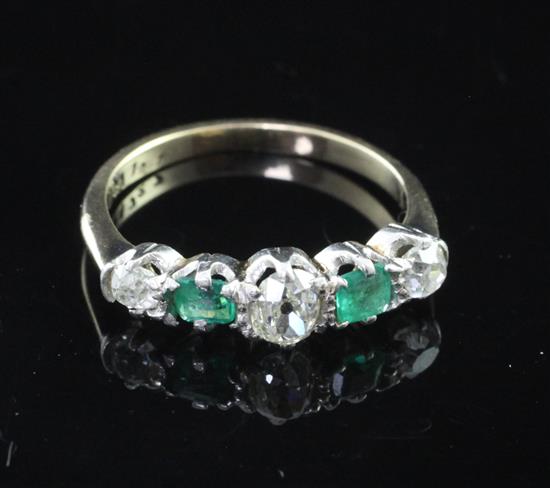 An early 20th century gold and five stone emerald and diamond half hoop ring, size L.